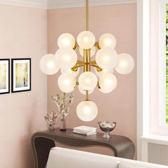 a chandelier hanging from the ceiling in a room with pink walls and white furniture