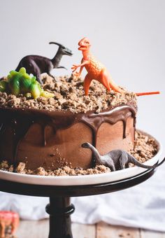 a chocolate cake topped with toy dinosaurs and sprinkles on top of it