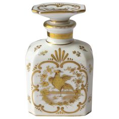 a white and gold decorated bottle with a bird on the front, sitting against a white background