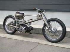 a silver motorcycle parked on the side of a road next to a garage door and sidewalk