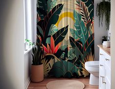 a bathroom with a shower curtain decorated with tropical leaves and plants, along with a rug on the floor