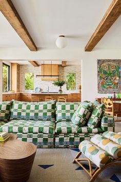 a green and white checkered couch in a living room with wood beams on the ceiling