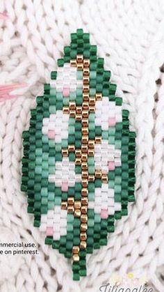 a green and white beaded brooch with gold accents on it's side