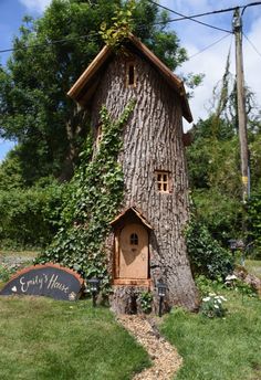 a tree house with ivy growing on it's side and a sign in front