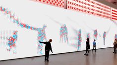 people are standing in front of a large wall with red and blue dots on it