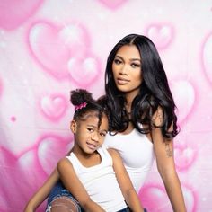 a mother and daughter posing for a photo in front of a pink background with hearts