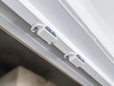 two white electrical devices are attached to the side of a building's window sill