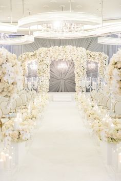 the aisle is decorated with white flowers and candles