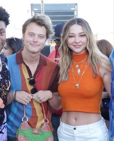 three people standing next to each other in front of a crowd at an outdoor event