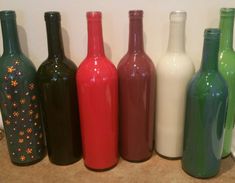 six different colored bottles lined up in a row on top of a counter next to a stove