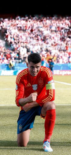 a soccer player squatting down on the field in front of an arena full of people