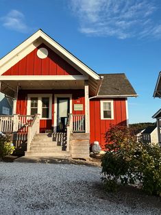 a red house with white trim on the front porch and steps leading up to it