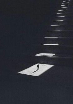 a person standing in front of some stairs with their shadow on the ground and light coming through them