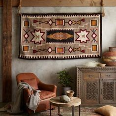 a living room with a rug hanging on the wall and a chair in front of it