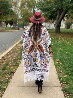 This Beautiful Hand Embroidered Poncho is perfect for keeping you warm and stylish at the same time. It has gorgeous hand embroidered details in both the front and back of the poncho. This poncho is handmade by Mexican Artisans and is completely one of a kind. Unisex Note: This poncho has open sides and comes in one size which is ideal for sizes, Small, Medium, Large, Extra Large, 2x, 3x. Bohemian Fall Kimono With Floral Embroidery, Bohemian Embroidered Kimono For Vacation, Bohemian Woven Poncho For Fall, Fall Bohemian Woven Poncho, Bohemian Embroidered Kimono With Kimono Sleeves, Embroidered Long Sleeve Poncho For Festival, Bohemian Kimono With Intricate Embroidery, Winter Embroidered Long Sleeve Poncho, White Cotton Kimono For Fall