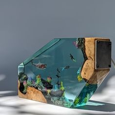 an artistic glass sculpture with animals and plants on it's side, in front of a gray background