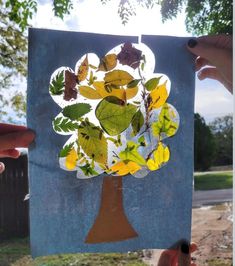 someone holding up a piece of paper that has been cut out to look like a tree