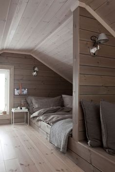 a bed sitting in the corner of a room under a slanted roof next to a window