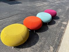 four brightly colored poufles sitting on the pavement