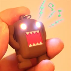 a hand holding a small toy with lights on it's face and mouth, in the shape of a monster