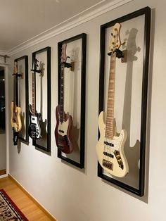 four guitars are hanging on the wall next to each other