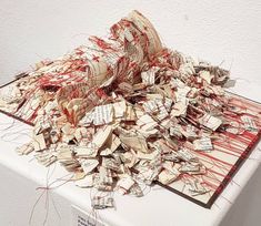 a pile of papers sitting on top of a white table covered in red and black thread