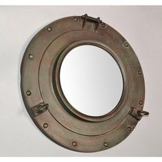 a metal porthole mirror mounted to the side of a wall