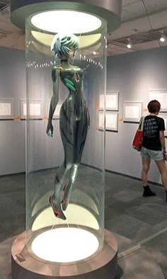 a woman standing in front of a glass case with a mannequin on it