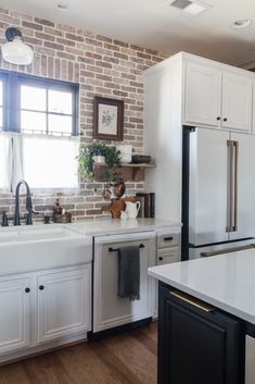 a kitchen with white cabinets and brick wall behind the countertop, along with an island