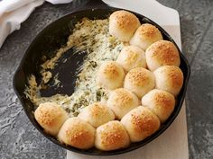 a cast iron skillet filled with cheese and rolls