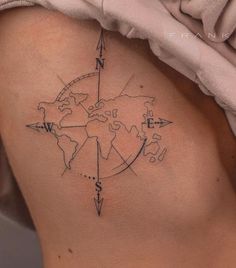 a woman's back with a compass tattoo on her left side ribcage