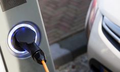 an electric car plugged in to a charger with blue light coming from it