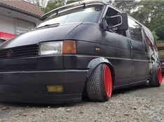 a van parked in front of a house with red rims on it's tires