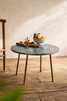 a bowl of fruit sitting on top of a table next to a wooden rocking chair