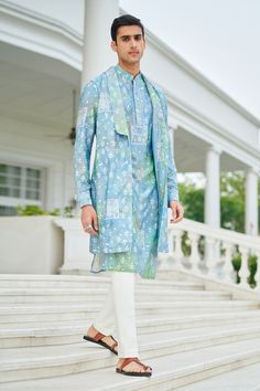 Blue silk long jacket with pintucked shawl lapel collar, patch pockets, all over floral, peacock and abstract print. Paired with mandarin collar printed kurta with crochet lace work  details and off white trousers with side pockets.
Components: 3
Pattern: Printed
Type Of Work: Floral, Peacock and Abstract Print
Neckline: Bundi: Shawl Lapel Collar, Kurta: Mandarin Collar
Sleeve Type: Bundi: Sleeveless, Kurta: Full Sleeves
Fabric: 100% Silk
Color: Blue
Other Details: 
Pintucked collar
Occasion: Sa Collar Kurta, Sleeveless Kurta, Floral Peacock, White Trousers, Nehru Jackets, Indian Attire, Long Jacket, Fashion App, Blue Silk