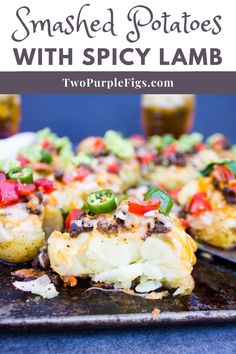 smashed potatoes with spicy lamb and peppers on a serving platter next to two glasses of beer