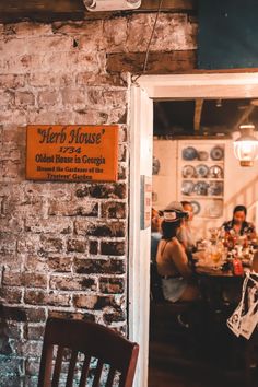 people sitting at tables in a restaurant with brick walls and doors open to the dining area