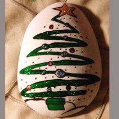 an egg decorated with green and white christmas trees