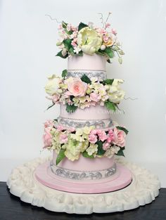 a three tiered cake with pink and white flowers on top