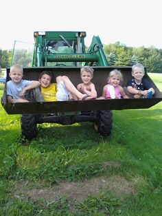 four children are sitting in the back of a tractor with their arms around each other