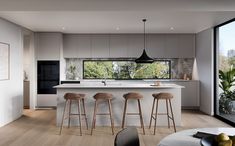 a modern kitchen with bar stools next to the counter and an open floor plan