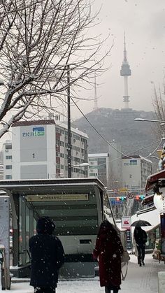 two people walking in the snow near a bus