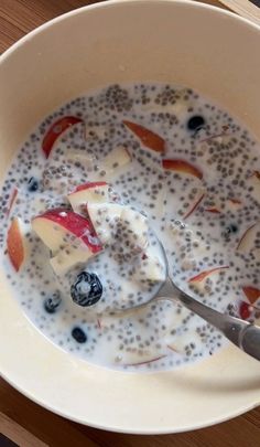 a bowl of oatmeal with apples and blueberries in it on a table