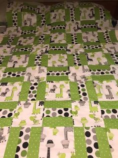 a green and white quilt on top of a bed covered in polka dotty fabric