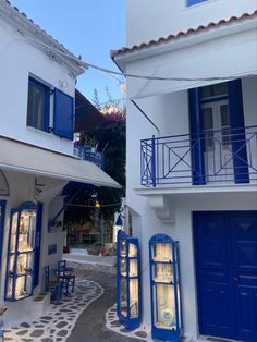 two buildings with blue doors and windows on the outside, one has an open balcony