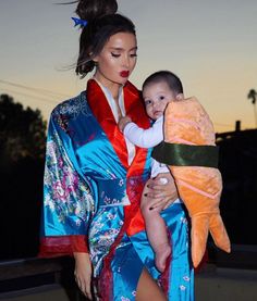 a woman holding a baby in her arms and wearing a kimono on the other side