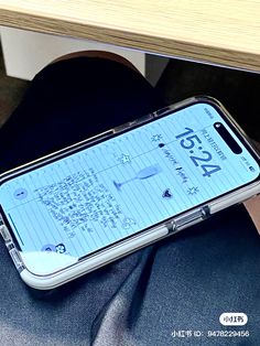 an iphone case with writing on it sitting next to a person's legs and desk