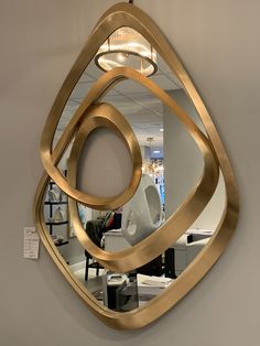 a mirror that is on the wall in front of a desk and some chairs behind it