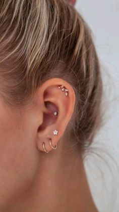 a close up of a woman's ear with two piercings on it and one behind her ear