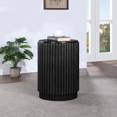 a black trash can sitting on top of a carpeted floor next to a potted plant